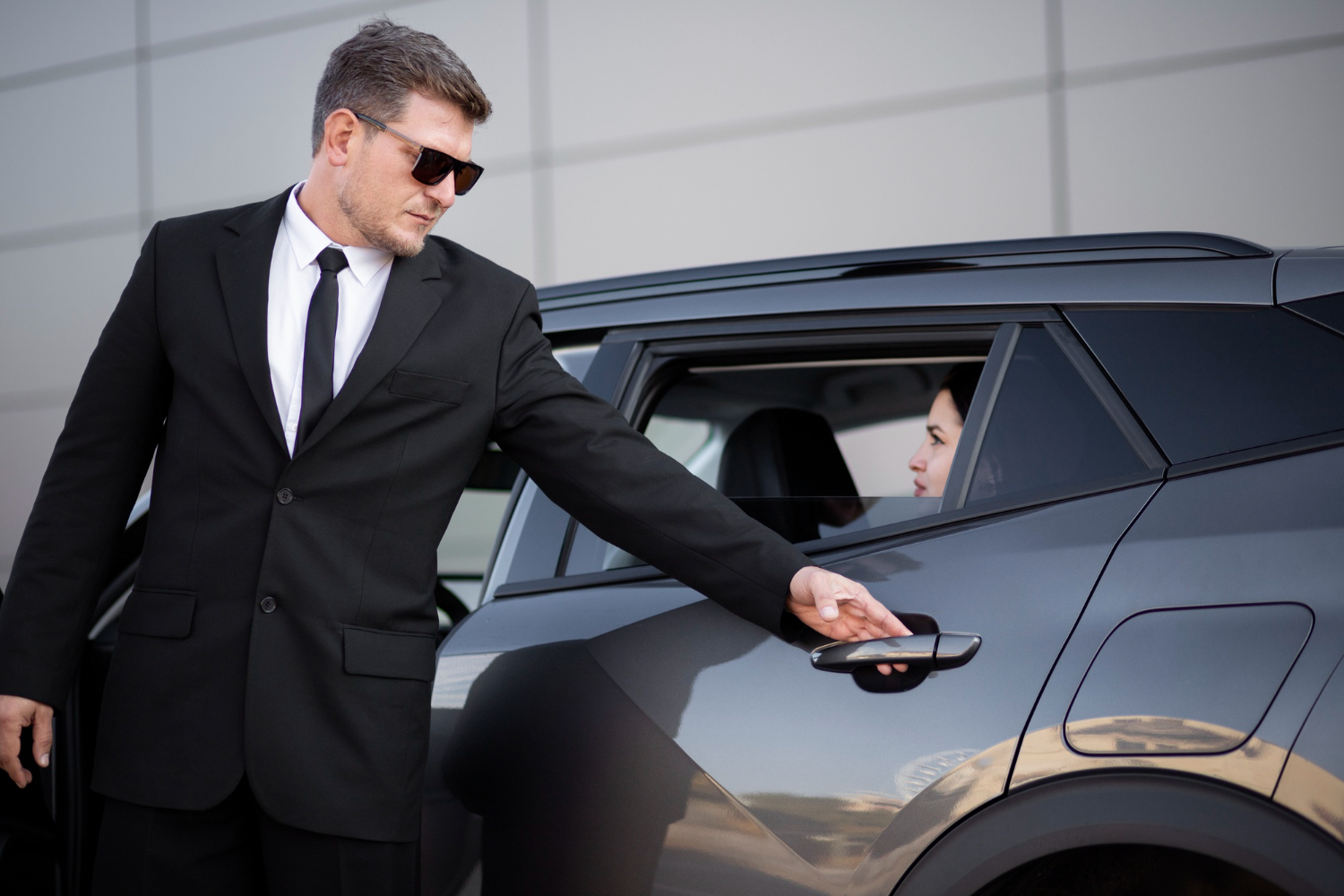 Chauffeur privé atra à Gaillac ouvrant une berline noire pour une cliente élégante