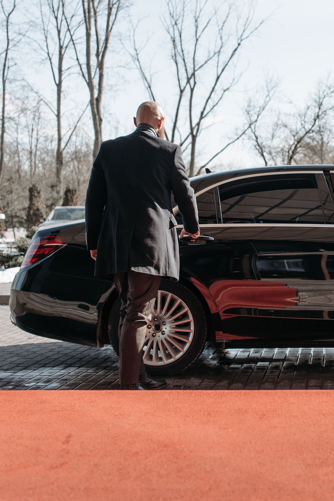 Chauffeur atra ouvrant une berline de luxe sur tapis rouge lors d’un événement prestigieux à Gaillac