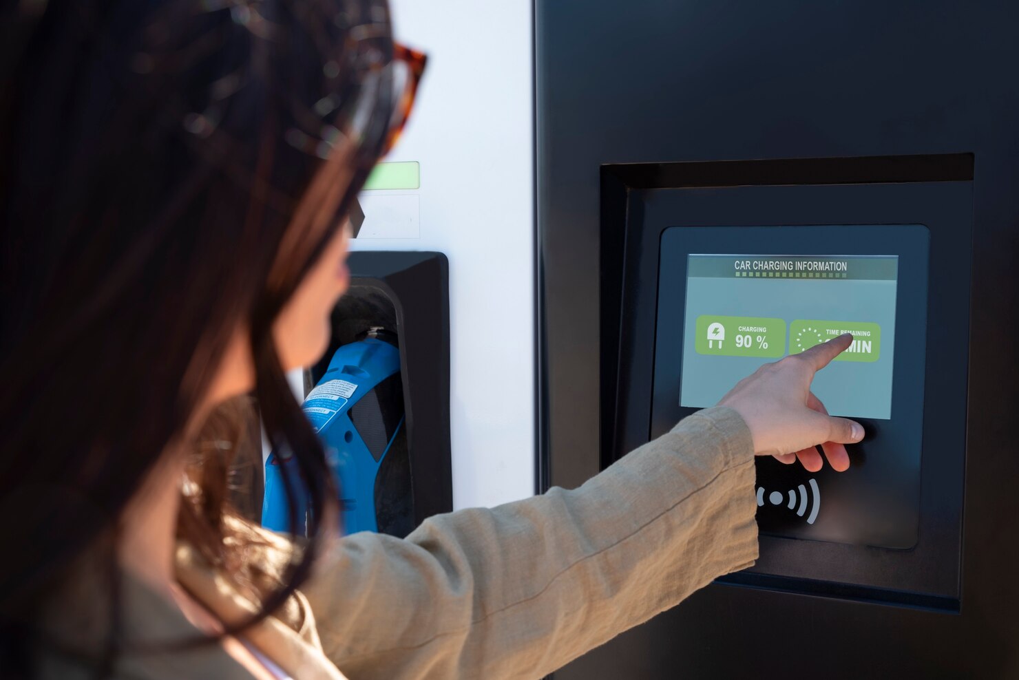 Recharge voiture électrique sur borne atra à gaillac, femme consultant l’écran tactile de charge